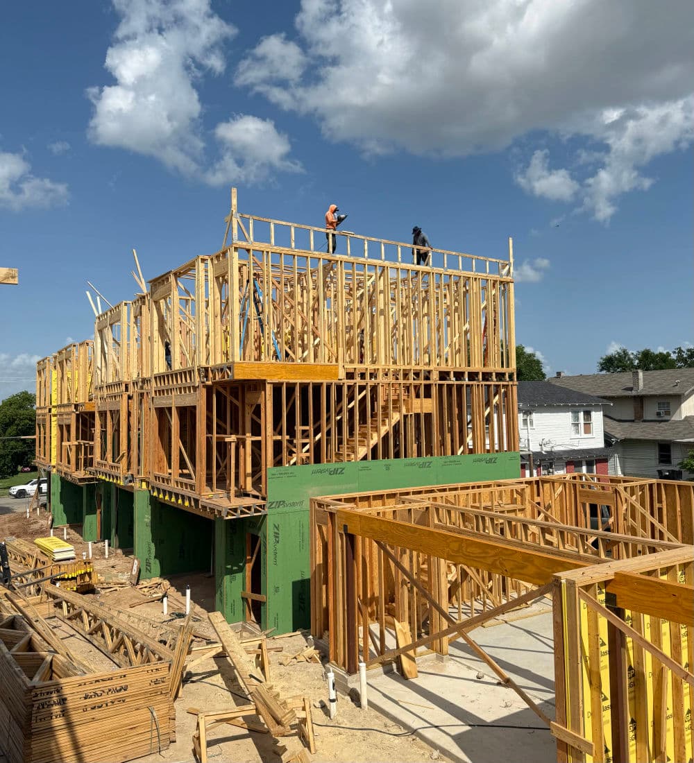Construction site with carpenters building wooden frames under a bright blue sky.